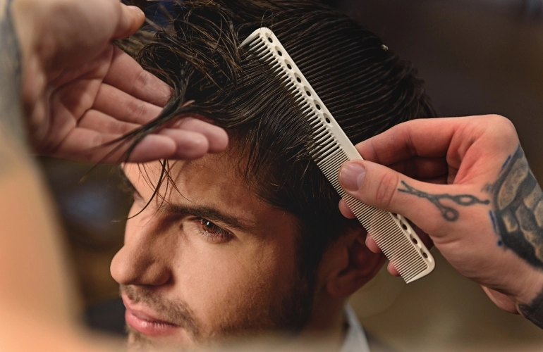 Osoba rozczesująca włosy mężczyźnie grzebieniem
